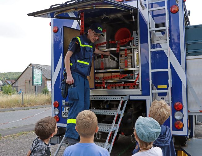 Feuerwehrmann erklärt Kindern die Ausrüstung am Auto